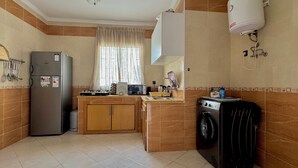 Een functionele keuken met een koelkast, magnetron, spoelbak en wasmachine.