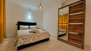 Een slaapkamer met een bed, nachtkastje, spiegel en plafondlamp.