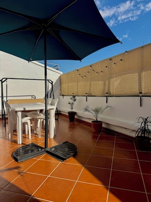 A patio with a table and chairs, potted plants, and a large umbrella. - Apartment Sunny Terrace (Tanger)