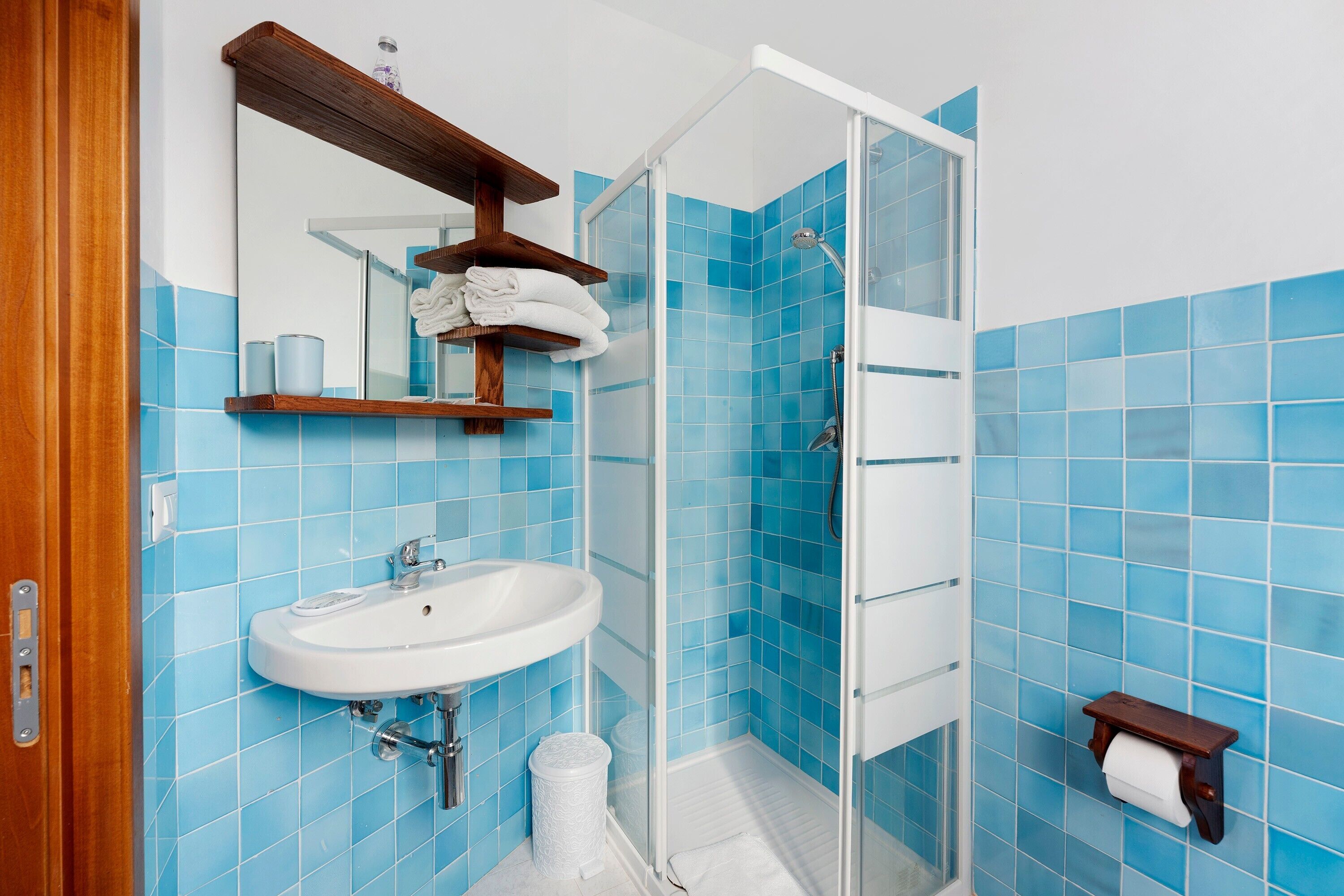 Une salle de bain avec un lavabo, un miroir, une douche et des carreaux bleus.