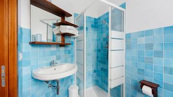 Une salle de bain avec un lavabo, un miroir, une douche et des carreaux bleus.