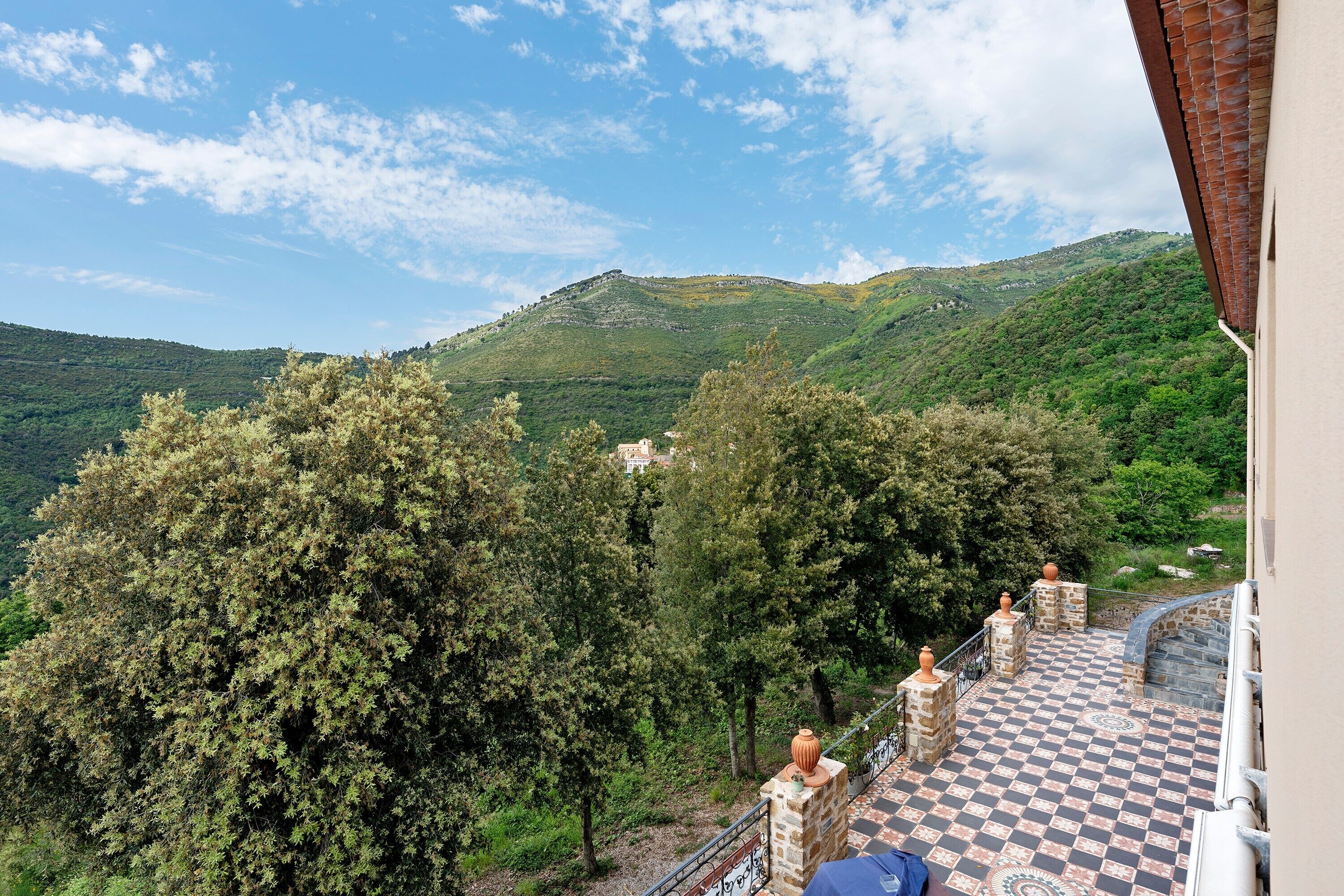 A terrace with a checkered floor, stone balustrades, and a view of a mountainous landscape.
