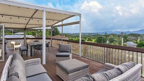 Une terrasse extérieure couverte, aménagée avec des sièges et une table, et offrant une vue sur le paysage.