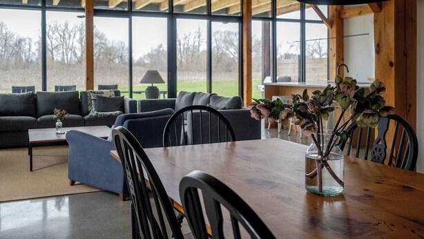 Un comedor con una mesa de madera, sillas y un jarrón con flores.