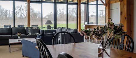 Un coin repas avec une table en bois, des chaises et un vase rempli de fleurs.