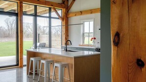 Una cocina con una isla grande, vigas de madera y ventanas amplias.