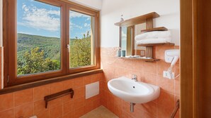A bathroom with a window, sink, mirror, towel rack, and a view of a green landscape. - Zenone Room with Sea View, Wi-Fi and Air Conditioning (Serramezzana)