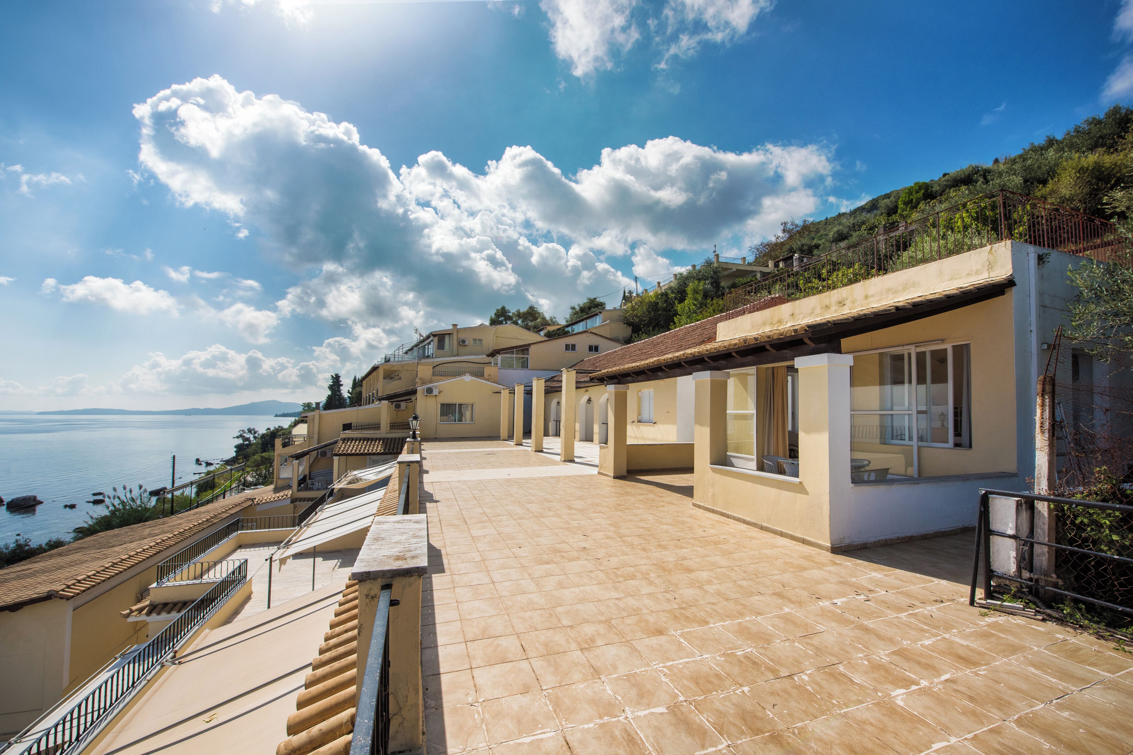 A coastal property with a terrace overlooking the sea, featuring multiple buildings with balconies and large windows.