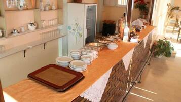 A breakfast buffet setup with plates, bowls, and a tray on a counter.