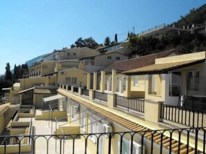 A row of yellow buildings with balconies and a staircase leading to the upper floors. - El Greco Hotel (Corfu)