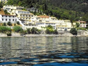 A coastal residential area with multi-story buildings, a waterfront, and a hilly backdrop.