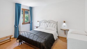 A bedroom with a bed, a bench, a bedside table, a nightstand, a window with curtains, and a ceiling light. - Room 'Camera Vico' with Mountain View, Wi-Fi and Air Conditioning (Serramezzana)
