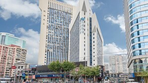 Un hotel moderno con una facciata triangolare caratteristica, diversi piani e un cartello ben visibile.