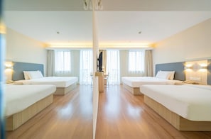Una habitació d'hotel amb dos llits, un escriptori i una finestra gran.
