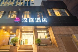 A hotel entrance with a sign, steps, and potted plants. - Hanting Hotel (shanghai North Bund Xinhua Hospital (Shanghai)