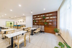 A modern library with bookshelves, seating, and tables. - Hanting Hotel (shanghai North Bund Xinhua Hospital (Shanghai)