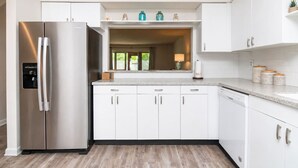 Une cuisine moderne avec des meubles blancs, un réfrigérateur en acier inoxydable et un plan de travail agrémenté de bocaux décoratifs.