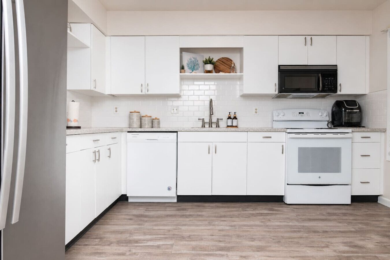 A modern kitchen with white cabinetry, a microwave, an oven, and a toaster.