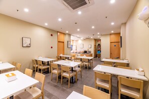 Un restaurante con varias mesas y sillas, una barra con alimentos y un equipo de aire acondicionado en la pared.