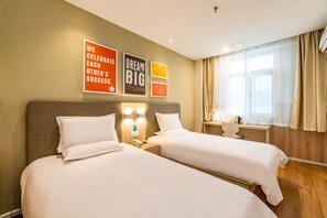 Habitación de hotel con dos camas, una mesita de noche con teléfono y carteles motivacionales en la pared.
