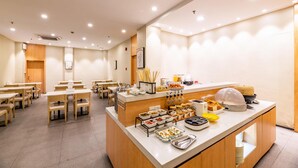 A dining area with tables and chairs, a buffet counter with food items, and a wall-mounted air conditioning unit. - Hanting Hotel Hangzhou West Lake Culture Squa (Hangzhou)