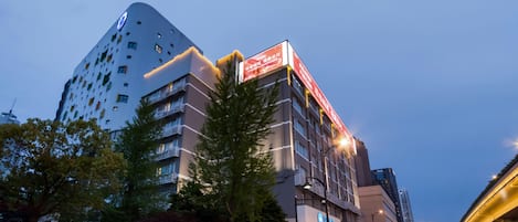 Un hotel de varios pisos con un diseño moderno, que destaca una señalización llamativa y una fachada bien iluminada.