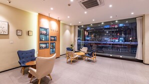 A modern hotel lobby with seating, a wooden accent wall, and a large window with a city view. - Hanting Hotel Hangzhou West Lake Culture Squa (Hangzhou)