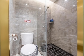 A bathroom with a glass-enclosed shower, a toilet, and a shelf with toiletries. - Hanting Hotel (shanghai South Shanxi Road Metro St (Shanghai)