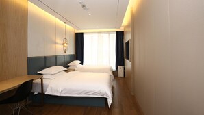 Habitación de hotel con dos camas, un escritorio, una silla, un televisor y una ventana con cortinas.