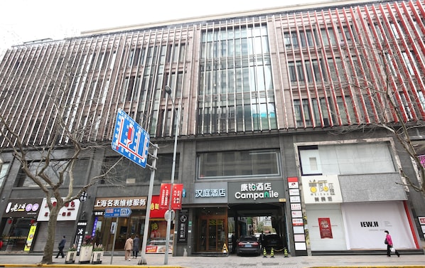 A modern building with large windows, a sign for a hotel, and various storefronts. - Hanting Hotel (shanghai South Shanxi Road Metro St (Shanghai)
