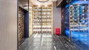 Un lobby de hotel moderno con piso de mármol, una estantería con diversos objetos y una vitrina de vidrio.