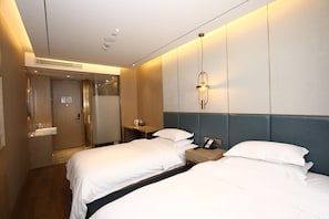 A hotel room with two beds, a bedside table with a phone, a wall-mounted light fixture, and a bathroom with a sink and mirror. - Hanting Hotel (shanghai South Shanxi Road Metro St (Shanghai)