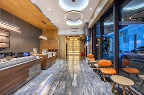 A modern hotel lobby with a reception desk, seating area, and a view of the street through large windows. - Hanting Hotel (shanghai South Shanxi Road Metro St (Shanghai)