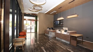 Un área de recepción con mostrador de madera, una zona de estar con sillas y un diseño de techo moderno.