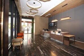 Un área de recepción con mostrador de madera, una zona de estar con sillas y un diseño de techo moderno.