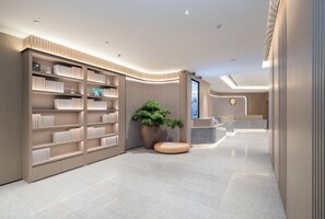 En moderne lobby med en reception, en stor reol og en potteplante.