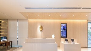 A modern reception area with a wooden reception desk, a digital display, and a seating area with a computer monitor. - JI Hotel JI Hotel (xinpu Roa (Nanjing)