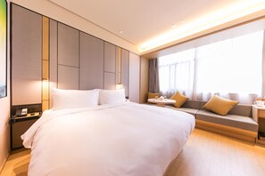 A hotel room with a large bed, bedside table, lamp, and a sofa with cushions. - Ji Hotel (hangzhou Future Science and Technology C (Hangzhou)
