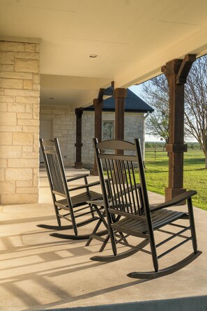 Ein überdachter Patio-Bereich mit zwei Schaukelstühlen und einer Steinmauer.