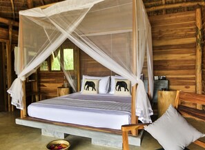 Una cabaña de madera con una cama con dosel, una mesita y un banco.