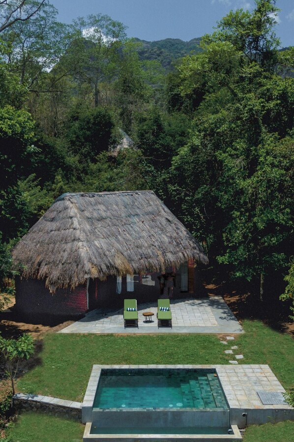 A thatched-roof hut with a pool and lounge chairs. - Gal Oya Lodge (MADULLA)