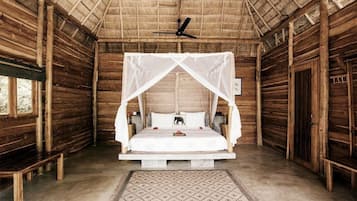A wooden room with a bed under a canopy, a ceiling fan, and a bench.