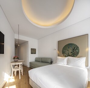 A modern bedroom with a bed, a desk, a chair, and a painting on the wall. - Lisbon Serviced Apartments Madalena (Lisbon)