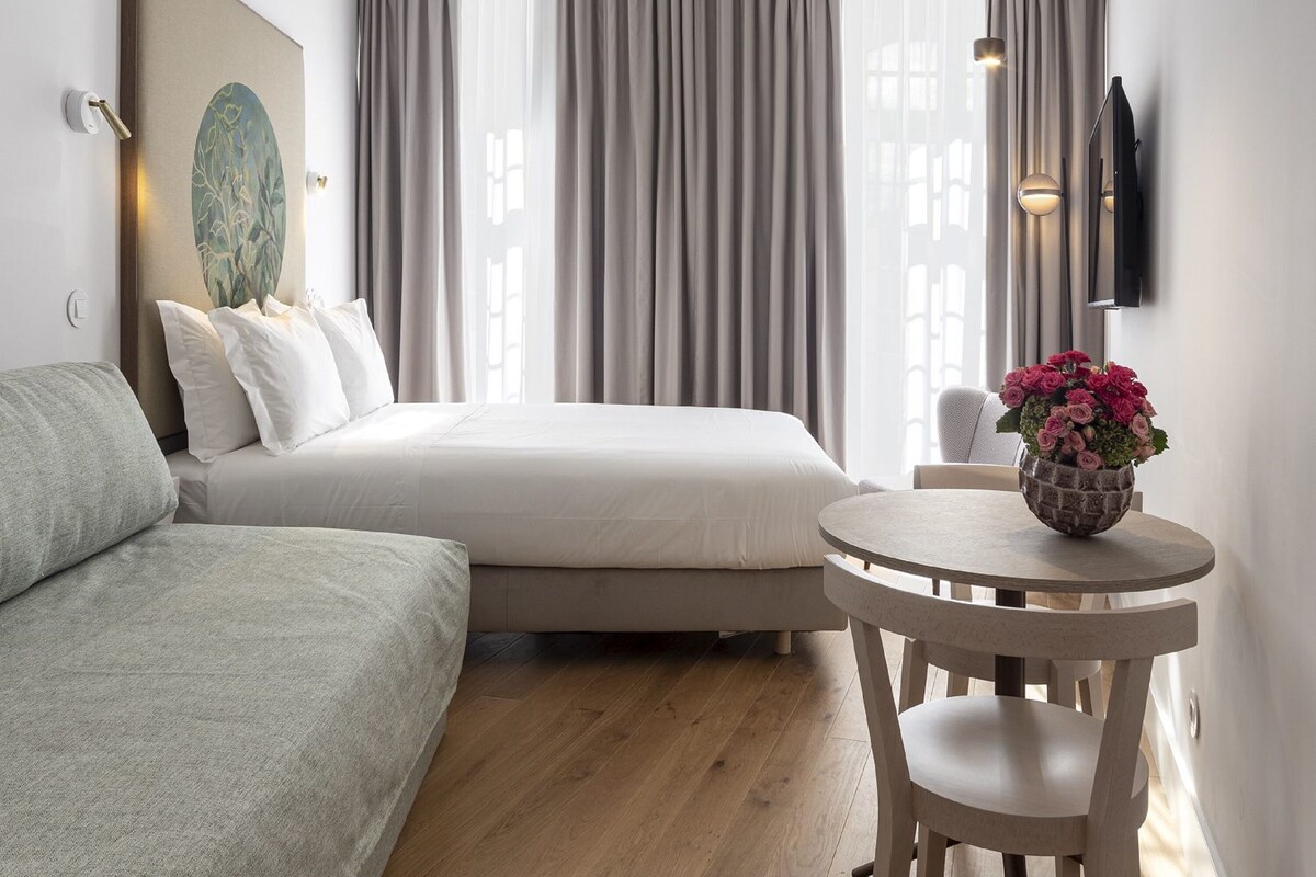 Habitació d'hotel moderna amb llit, una taula rodona i un quadre a la paret.
