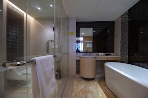 Un baño moderno con cabina de ducha de vidrio, una bañera independiente y un lavamanos con espejo.