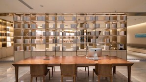 A modern library with a large wooden table and chairs, surrounded by bookshelves. - Ji Hotel Hangzhou East Railway Station Qiutao N R (Hangzhou)