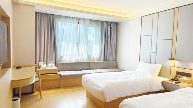 A hotel room with two beds, a desk, a window with curtains, and a large mirror. - Ji Hotel Hangzhou East Railway Station Qiutao N R (Hangzhou)