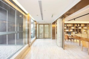 Un interior modern amb una paret de vidre, un taulell de recepció de fusta i una prestatgeria.