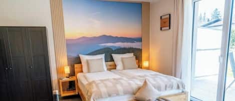 A bedroom with a large bed, a nightstand, a wardrobe, and a scenic wall mural.