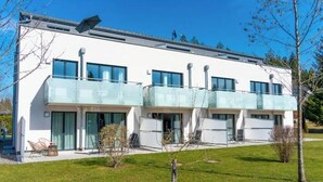 Ein modernes Gebäude mit flachem Dach, großen Fenstern und einem Balkon.